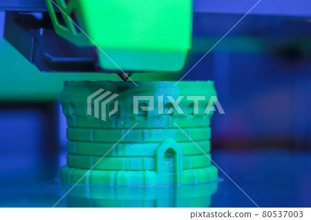 Modern 3D printer machine printing green plastic model at exhibition - close up 80537003