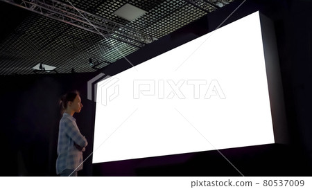 Woman looking at blank large interactive wall display - white screen concept 80537009