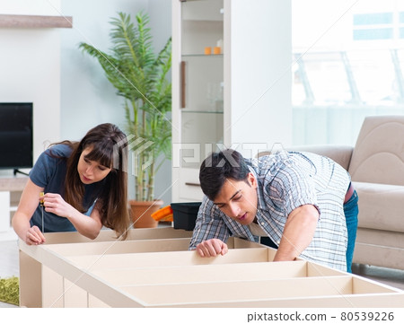 Young family assembling furniture at new house 80539226