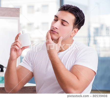 Young handsome man applying face cream Young handsome man applying face cream 80539408