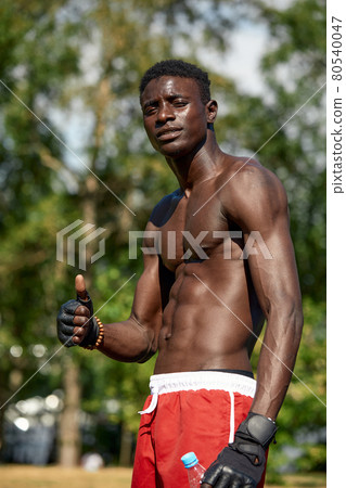 Shirtless african american man showing thumbs up, while training on the sports ground in the park, the athlete shows that he is doing fine Shirtless african american man showing thumbs up, while training on the sports ground in the park, the athlete shows that he is doing fine 80540047