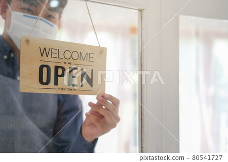 Young business owner wear face mask and opening sign. Young business owner wear face mask and opening sign. 80541727