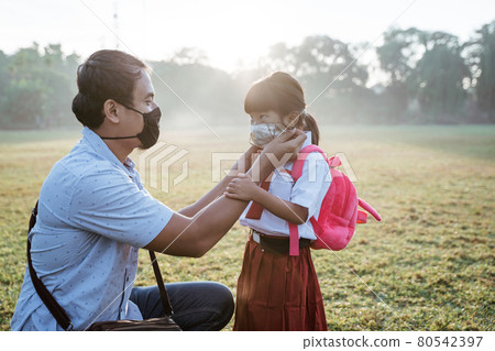 father helping her daughter to wear a mask before going to school father helping her daughter to wear a mask before going to school 80542397