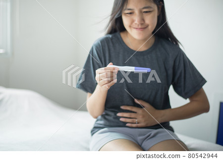 Asian female hand touching her belly after testing pregnancy test at home Asian female hand touching her belly after testing pregnancy test at home 80542944