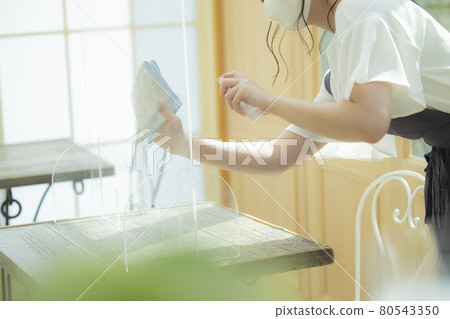 A restaurant clerk who disinfects 80543350