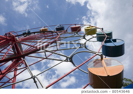 Ferris wheel against the background of a blue sky with clouds. 80543646