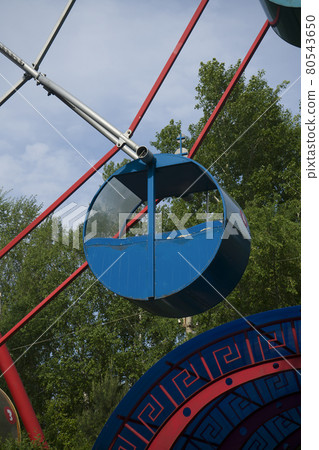 Blue cabin of the round shaped Ferris wheel against the background of the blue sky. Blue cabin of the round shaped Ferris wheel against the background of the blue sky. 80543650