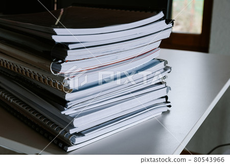 Stack of reports lies on a desk ready for review 80543966