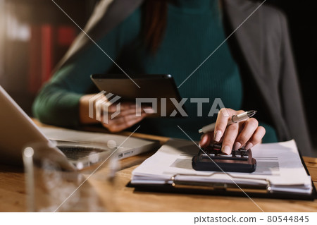 justice and law concept.businessman or lawyer or accountant working on accounts using a smart phone laptop digital tablet  calculator  and documents in dark office . 80544845