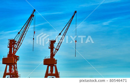 Cargo cranes on the harbor quay against a sky with hazy veil clouds Cargo cranes on the harbor quay against a sky with hazy veil clouds 80546471