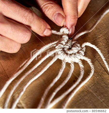 First knots to make a macrame coaster from a rope on a plate of wood First knots to make a macrame coaster from a rope on a plate of wood 80546662