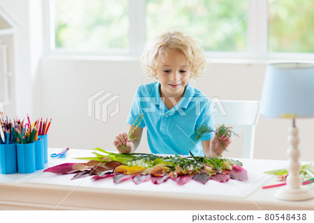 Child creating picture with colorful leaves. 80548438