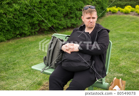 Unhappy Man with backpacks waiting public transport in city. Commuting, travelling, transportation concept 80549078