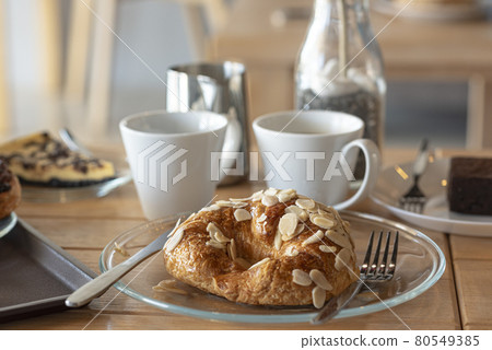 Sweet Croissant almond server with americano and latte and chocolate tart on wooden desk in cafe. 80549385