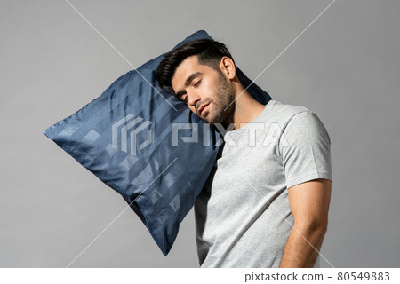 Young sleeping man holding his pillow standing, sleepwalking concept 80549883