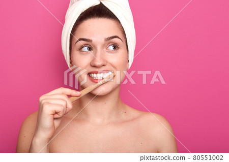 Cheerful charming lady standing isolated over pink background in studio, looking aside, having perfect white smile, keeping her skin in good condition, brushing her teeth in morning. Hygiene concept. Cheerful charming lady standing isolated over pink background in studio, looking aside, having perfect white smile, keeping her skin in good condition, brushing her teeth in morning. Hygiene concept. 80551002