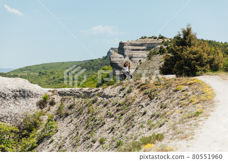 a beautiful woman walking along a mountain road on a hiking trip a beautiful woman walking along a mountain road on a hiking trip 80551960