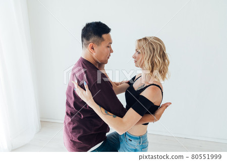a man and a woman dance bachata to music in a white room 80551999