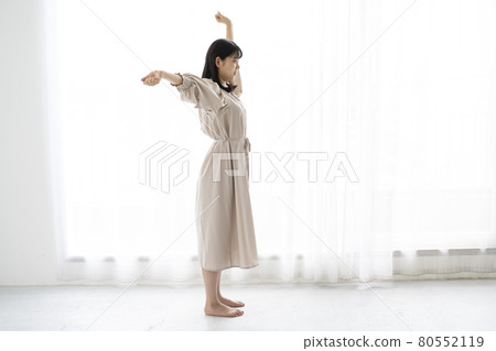 Young woman stretching barefoot in the room 80552119