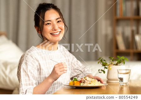 Young woman eating at night 80554249