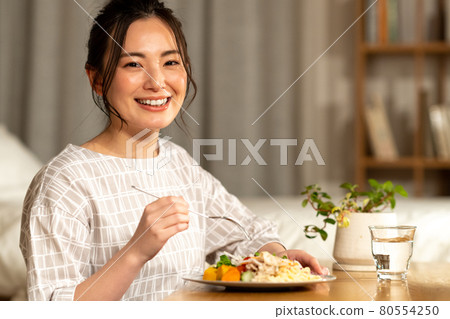 Young woman eating at night 80554250
