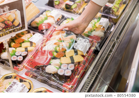Young woman picking up a sushi pack at a supermarket 80554380