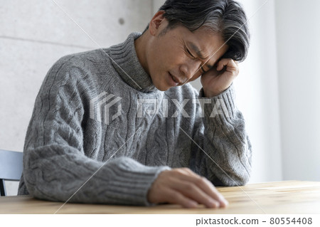 A man in his 50s holding his head A man in his 50s holding his head 80554408