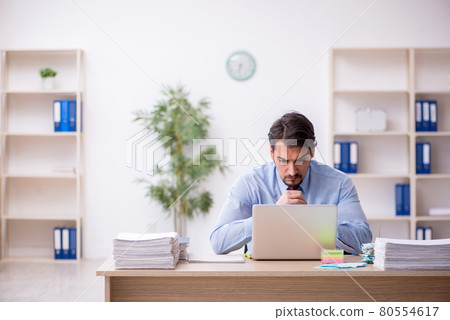 Young male employee and too much work in the office Young male employee and too much work in the office 80554617