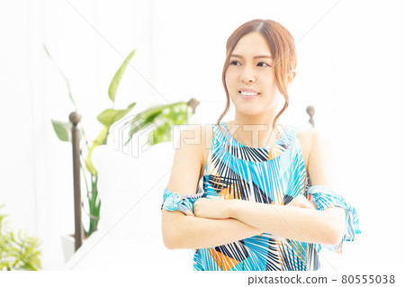 一位身著連體衣的年輕女子，在明亮的房間裡雙臂交叉在窗邊大笑 80555038