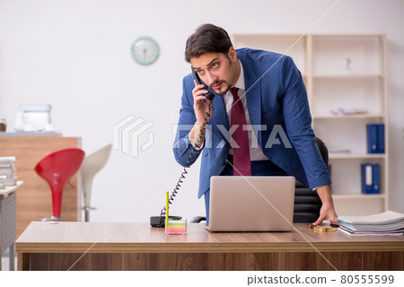 Young male employee sitting at workplace Young male employee sitting at workplace 80555599