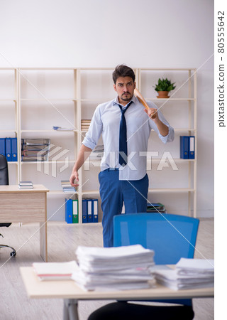 Young male employee unhappy with excessive work in the office Young male employee unhappy with excessive work in the office 80555642