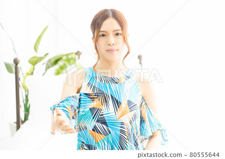 A young woman in a one-piece swimsuit gesturing a handshake by the window in a bright room A young woman in a one-piece swimsuit gesturing a handshake by the window in a bright room 80555644