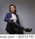 cool business woman in a jacket sitting in a chair on a dark background 80555795