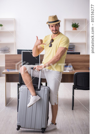 Young male employee preparing for trip at workplace Young male employee preparing for trip at workplace 80556277