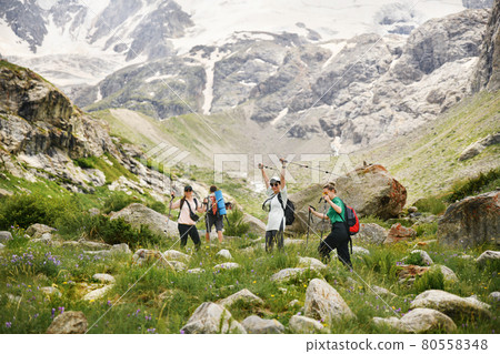 Women with backpacks and scandinavian sticks climb the mountains in Caucasus 80558348