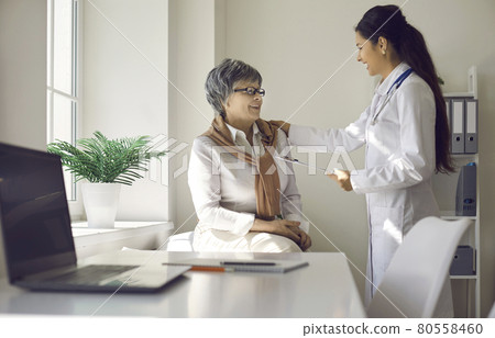 Female doctor has fun talking to an elderly woman who came to the clinic for a medical examination. 80558460