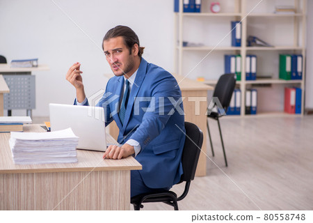 Young male employee and too much work in the office 80558748