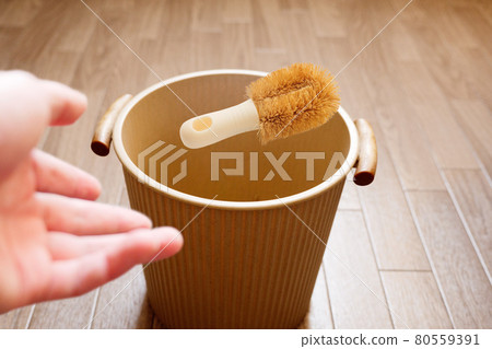 Throw the used turtle scrubbing brush into the trash can 80559391