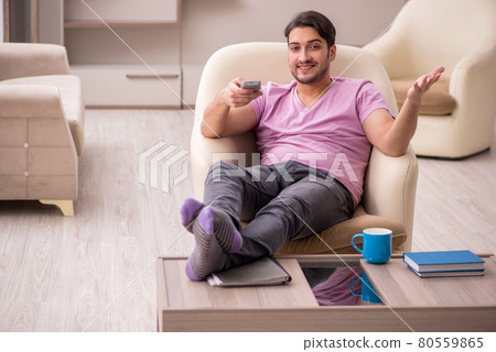 Young man watching tv at home during pandemic Young man watching tv at home during pandemic 80559865