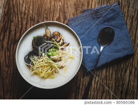 Rice porridge in bowl on wooden plate. 80560166