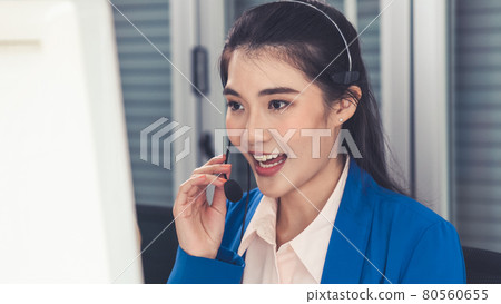Businesswoman wearing headset working actively in office Businesswoman wearing headset working actively in office 80560655