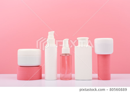 Set of cosmetic bottles with beauty products on geometric props against pink background  80560889