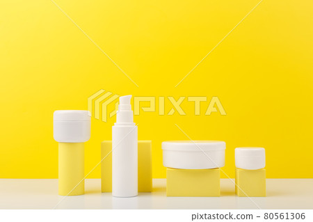 Set of cosmetic bottles with beauty products on geometric props against yellow background with copy space 80561306
