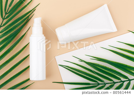 Top view of set of cosmetic bottles in white unbranded tubes for daily skin care routine against beige background. Top view of set of cosmetic bottles in white unbranded tubes for daily skin care routine against beige background. 80561444