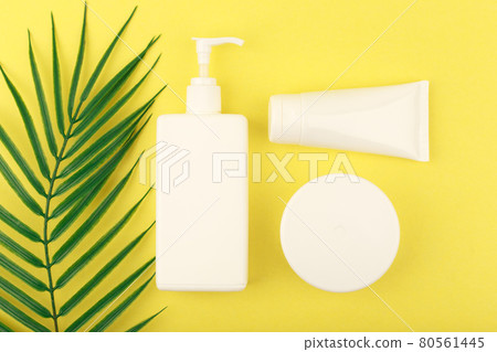 Top view of cosmetic products for self tanning on yellow background with palm leaf Top view of cosmetic products for self tanning on yellow background with palm leaf 80561445