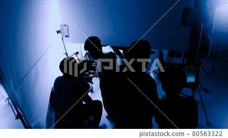 Video production behind the scenes. Making of TV commercial movie that film crew team lightman and cameraman working together with film director in studio. film production concept. Silhouette style. 80563322