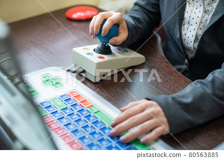 Woman with cerebral palsy works on a specialized computer. 80563885