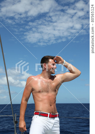 Young man sailing his boat on the open ocean Young man sailing his boat on the open ocean 80565124