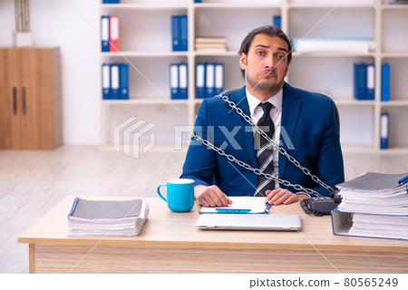 Chained male employee unhappy with excessive work in the ofiice 80565249