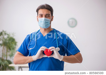Young male doctor cardiologist working in the clinic during pand Young male doctor cardiologist working in the clinic during pand 80566500